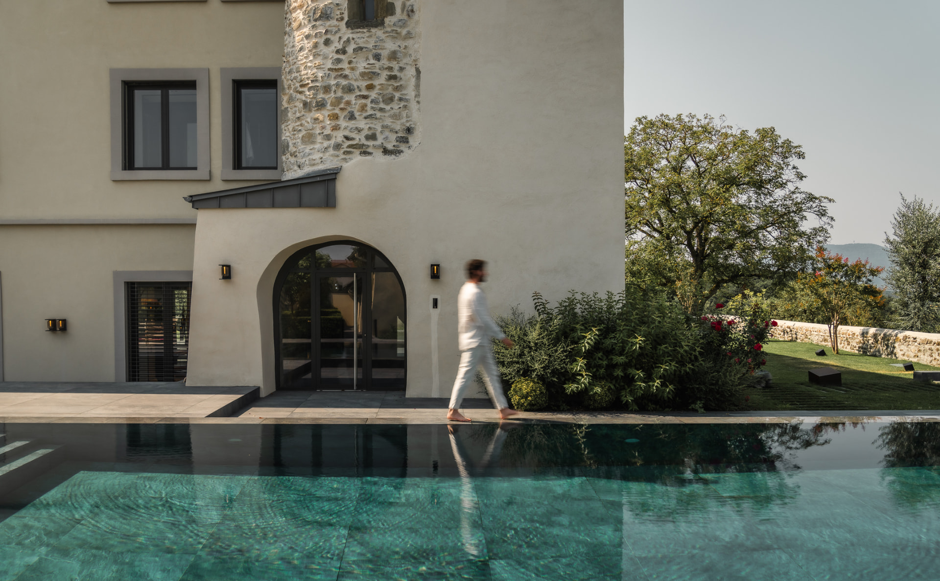 Villa contemporaine en pierre claire au bord d'une piscine à débordement, à l'aube